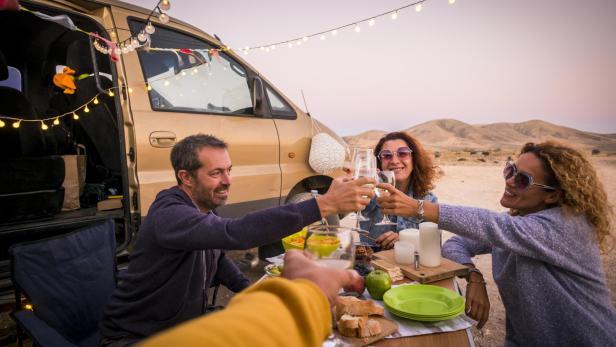 Freunde stoßen bei einem Campingausflug mit Wein an.
