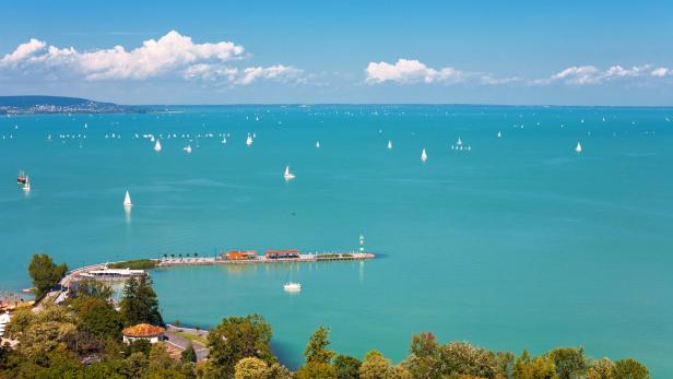 Blick auf den Balaton mit zahlreichen Segelbooten auf dem türkisfarbenen Wasser.