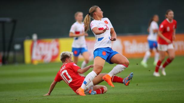 Eine Fußballspielerin im weißen Trikot wird von einer Spielerin im roten Trikot gefoult.