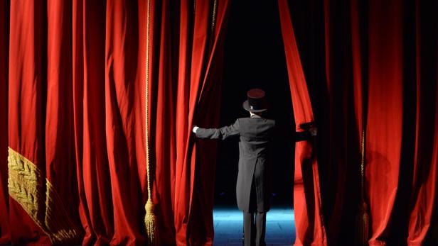 actor in a tuxedo stage curtain opens