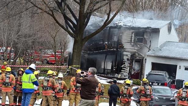 Feuerwehrleute stehen vor einem Haus, das durch einen Brand beschädigt wurde.