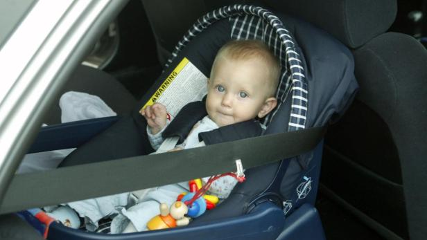 Ein Baby sitzt angeschnallt in einem Autositz.
