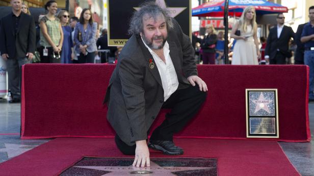 Peter Jackson kniet auf dem Hollywood Walk of Fame neben seinem Stern.