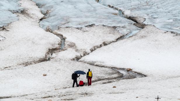 Touristen gehen auf den Resten des Gletschers auf der Zugspitze spazieren