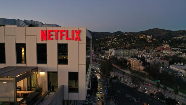 Das Netflix-Logo leuchtet rot auf einem Bürogebäude bei Dämmerung.
