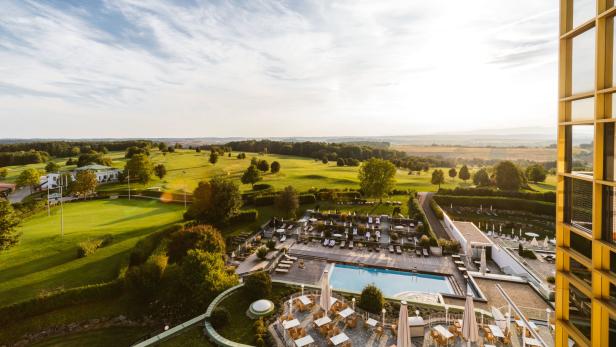 Blick auf einen Golfplatz und einen Hotelpool an einem sonnigen Tag.