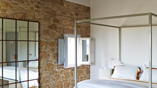 Ein Schlafzimmer mit einem Himmelbett und einer Wand aus Naturstein.