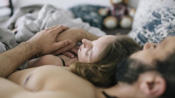 Ein Paar liegt eng umschlungen im Bett.