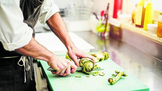 Chef cutting artichokes for dinner preparation - Man cooking inside restaurant kitchen - Focus on vegetable - Vegan cuisine, lifestyle and healthy food concept