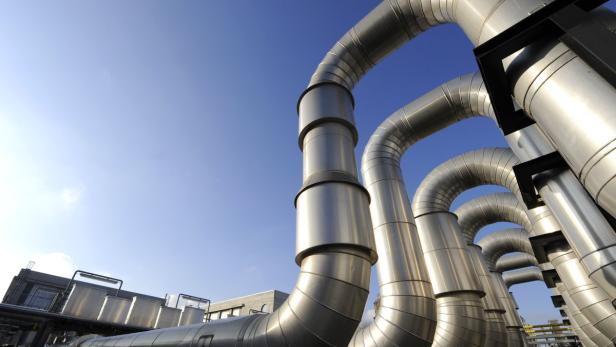 Silberne Rohre vor blauem Himmel auf einem Industriegelände.