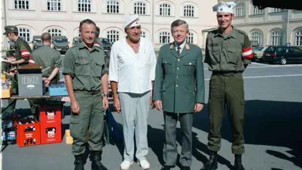Eine Gruppe von Männern in Uniformen und Zivilkleidung steht zusammen.