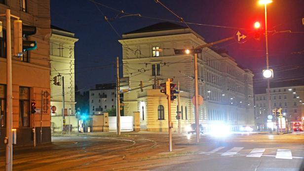 Eine nächtliche Straßenszene in einer Stadt mit beleuchteten Gebäuden und Ampeln.