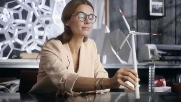 Eine Frau betrachtet ein Modell einer Windkraftanlage auf einem Tisch.