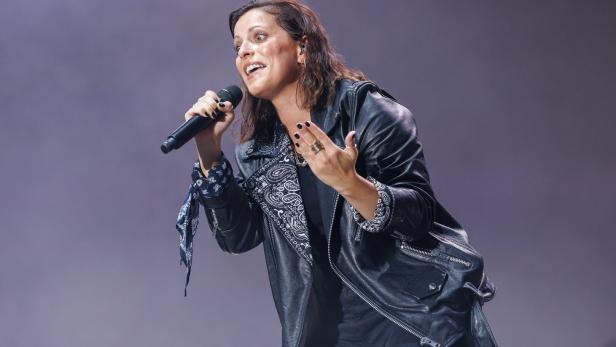 Stefanie Kloß mit Lederjacke und Mikrofon performt auf einer Bühne.