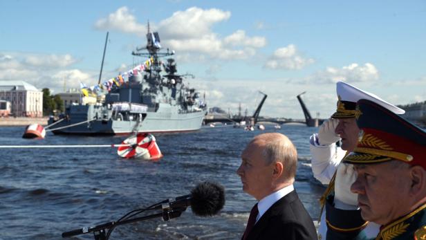 Putin hält im Vordergrund Rede, im Hintergrund schwimmt ein Militärschiff