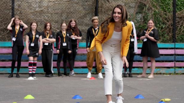 Prinzessin Kate spielt ein Spiel mit Wurfsäckchen und Hütchen vor einer Gruppe von Jugendlichen.