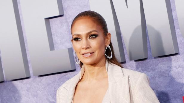 Jennifer Lopez trägt einen Blazer und Ohrringe.