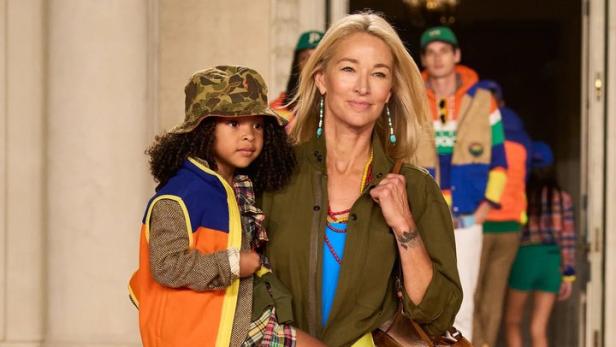 Eine Frau trägt ein Kind auf dem Arm, beide in Kleidung von Ralph Lauren.