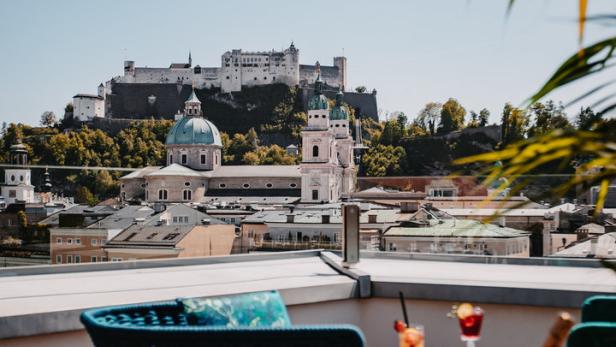 Blick von einer Dachterrasse auf die Festung Hohensalzburg und die Stadt Salzburg.