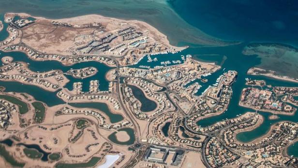 Luftaufnahme einer Küstenstadt mit vielen Wasserwegen und einem Yachthafen.