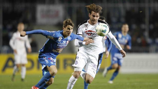 Zwei Fußballspieler kämpfen um den Ball während eines Spiels.