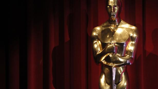 Eine goldene Oscar-Statuette vor einem roten Vorhang.