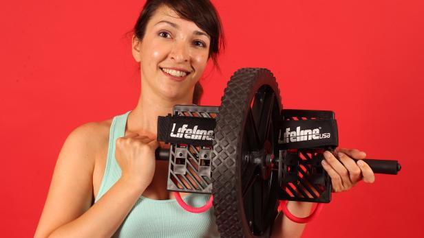 Eine Frau hält ein Lifeline USA Trainingsgerät vor einem roten Hintergrund.