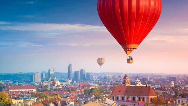Ein roter Heißluftballon über der Stadt Vilnius bei Sonnenaufgang.