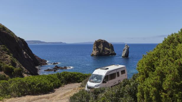 Ein Wohnmobil steht an der Küste mit Blick auf das Meer und Felsen.