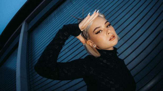 Mathea posiert vor einer blauen Wand für ein Interview.