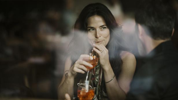 Frau genießt mit ihrem Freund einen Drink in einem Restaurant.