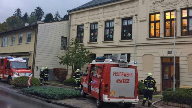 Feuerwehrleute stehen vor einem Gebäude mit einem Feuerwehrwagen.