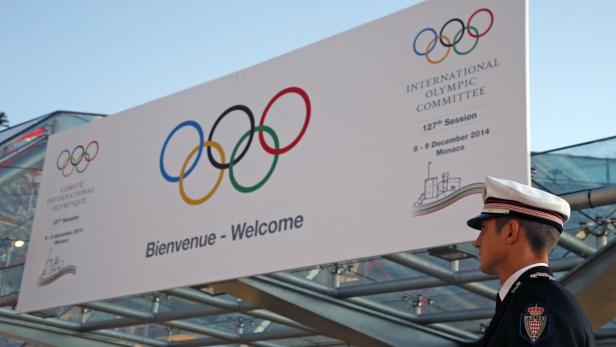 Ein Polizist steht vor einem Schild des Internationalen Olympischen Komitees in Monaco.
