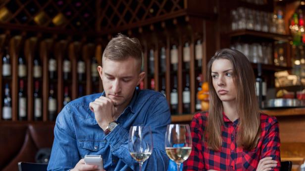Ein unglückliches Paar sitzt an einem Tisch in einer Bar.