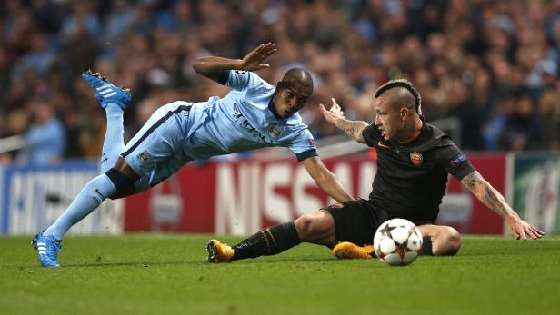 Ein Fußballspieler in hellblauem Trikot stürzt, während ein Spieler in Schwarz daneben sitzt.