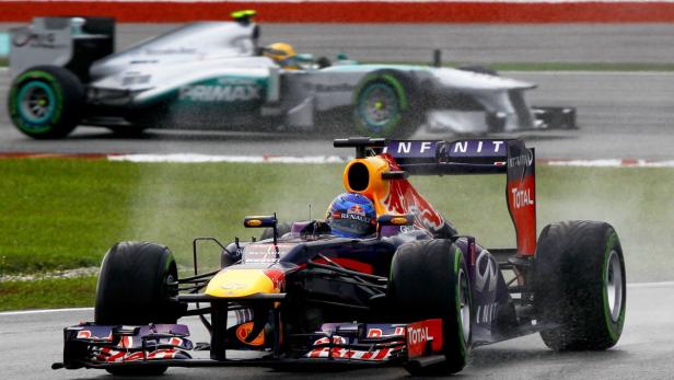 Zwei Formel-1-Autos fahren im Regen auf einer Rennstrecke.