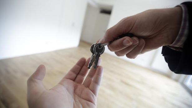 Eine Hand übergibt einem anderen die Schlüssel zu einem neuen Haus.