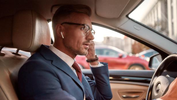 Mann im Anzug telefoniert im Auto.