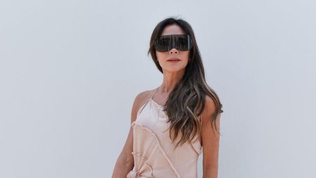 Victoria Beckham trägt ein hellrosa Kleid und eine übergroße Sonnenbrille.