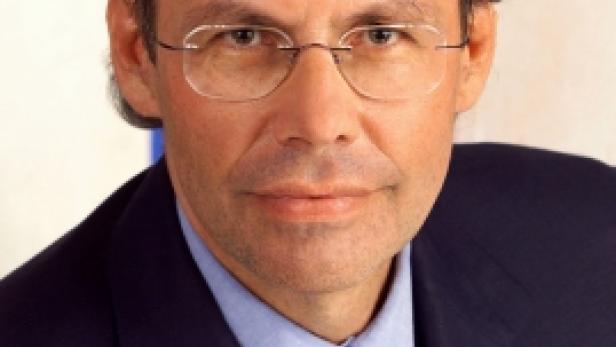 Ein Mann mit Brille, Anzug und Krawatte blickt in die Kamera.