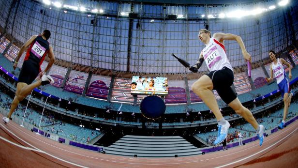 Athleten bei einem Staffellauf in einem Stadion.