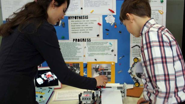 Eine Frau und ein Junge arbeiten an einem Roboterprojekt, das auf einem Tisch steht.