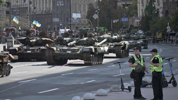 Panzer mit ukrainischer Flagge rollen durch eine bewachte Straße