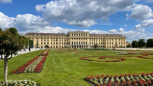 Das Schloss Schönbrunn mit seinem weitläufigen Garten unter einem bewölkten Himmel.