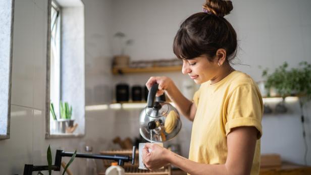 Eine junge Frau bereitet zu Hause Tee zu.