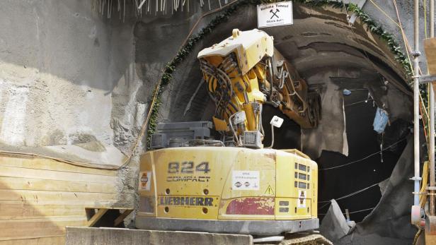 Ein gelber Liebherr-Bagger steht vor dem Eingang zum Renate-Tunnel.