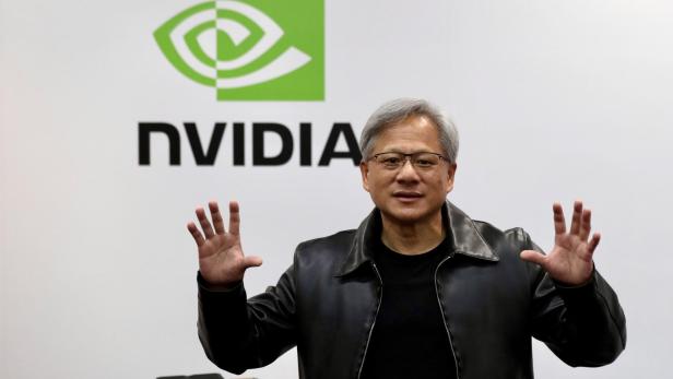 Nvidia-Chef Jensen Huang posiert vor dem Nvidia-Logo.