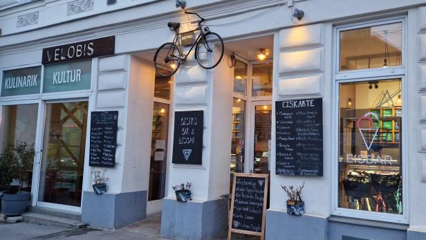 Das „Velobis“ ist Bistro, Bar und Eisbar; ein Fahrrad hängt als Dekoration über dem Eingang.