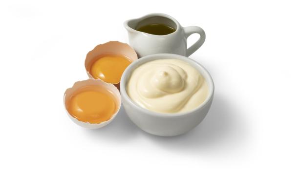 Mayonnaise in einer weißen Schale mit Eigelb und Öl.
