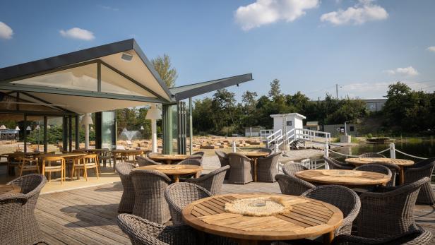 Ein Restaurant mit Tischen und Stühlen im Freien an einem sonnigen Tag.